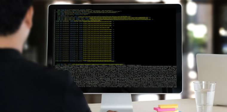 Hacker ético observando um monitor com várias linhas de código