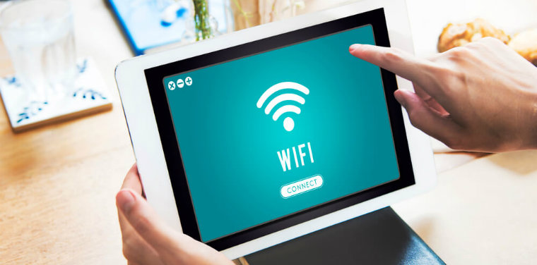 Pessoa segurando um tablet com a tela aberta com o ícone de "WIFI", menção a segurança de rede wifi