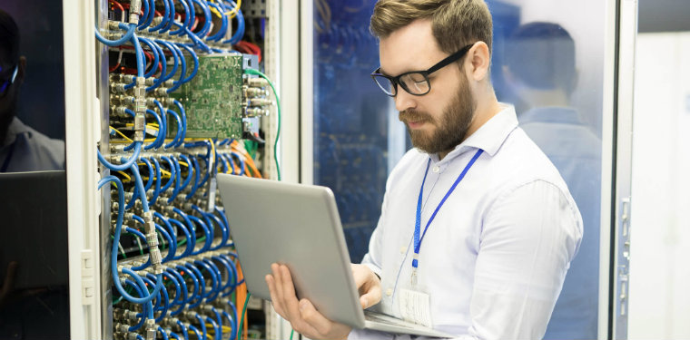 Homem usando óculos fazendo alterações em um rack, exemplo de gestão de data centers.